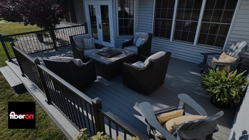 Backyard deck with black wicker seating around a square fire pit, beige cushions, and a Fiberon logo in the bottom-left corner.